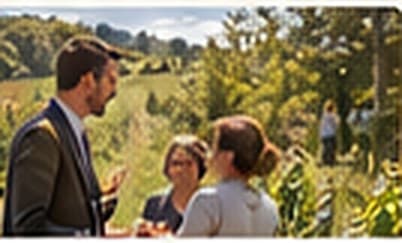 Un vigneron échange avec deux invitées au milieu des vignes.
